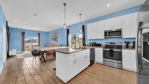 A modern kitchen with white cabinets, stainless steel appliances, and a large island. - Comfortable 4 bedroom 4 bath Home Near Disney (Davenport)
