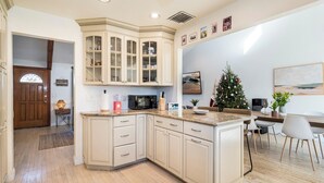 Een moderne keuken met een gebogen eiland, inbouwmeubels en een eethoek met een kerstboom.