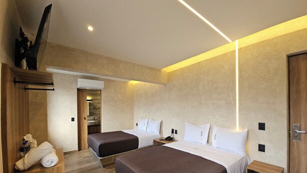 A hotel room with two beds, a wooden wardrobe, a bathroom, and a modern design. - Hotel Único La Villa (Mexico City)