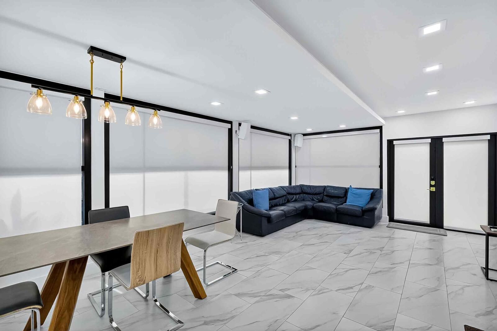 A modern interior with a dining table, chairs, a sofa, and a large window.
