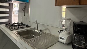 Eine Küche mit Gasherd, Spüle und Einbaugeräten wie Mixer und Kaffeemaschine.