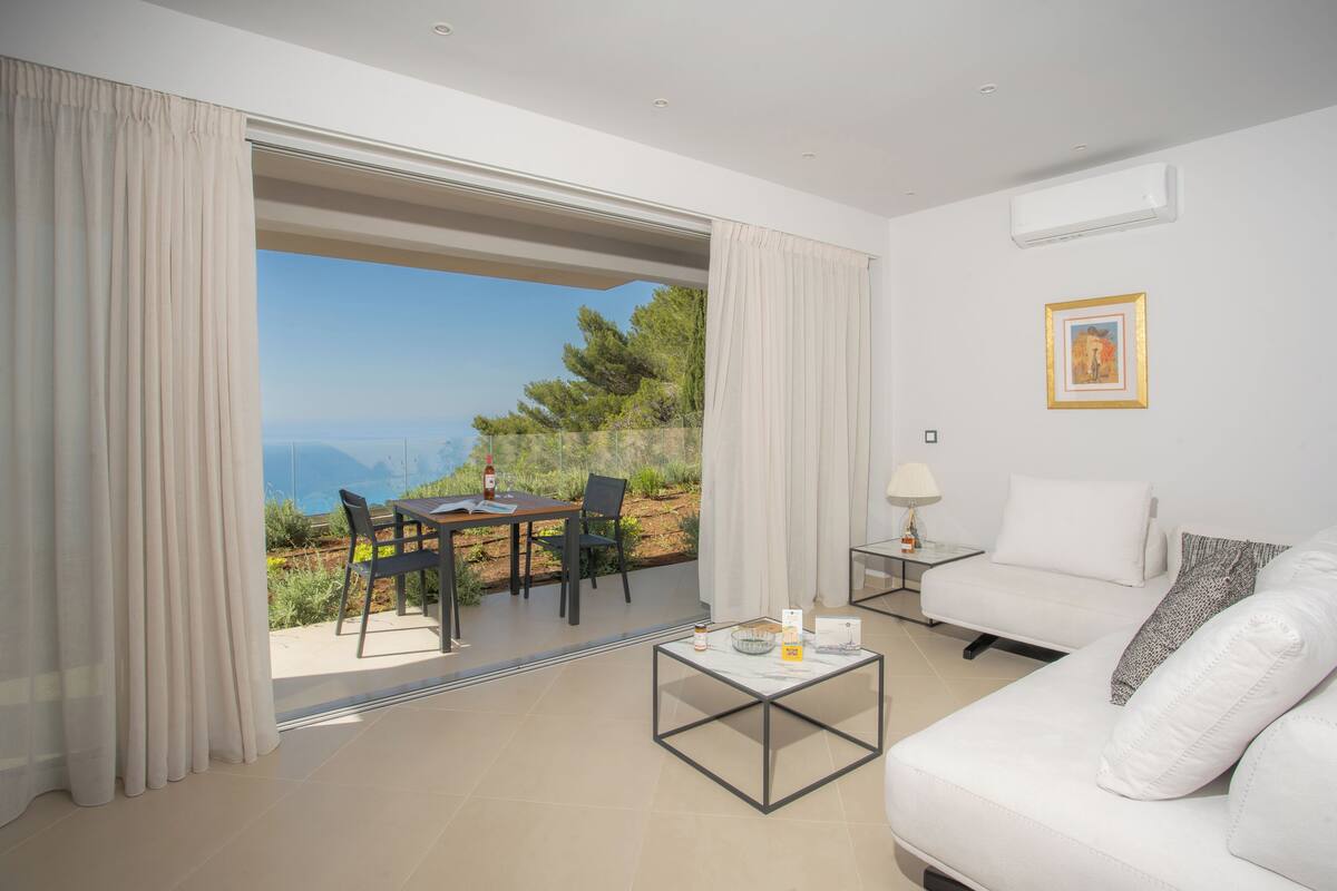 A modern room with a white sofa, a glass coffee table, and a view of the outdoors.