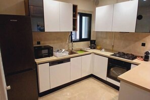 Eine kleine Küche mit Kühlschrank, Mikrowelle, Spüle und Herd.
