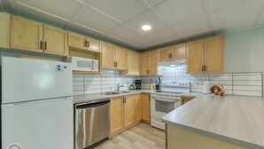 A modern kitchen with wooden cabinets, stainless steel appliances, and a light-colored countertop.