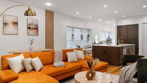 Ein modernes Wohnzimmer mit einem Ecksofa, einem runden Couchtisch und einer Küchenzeile mit Kochinsel.