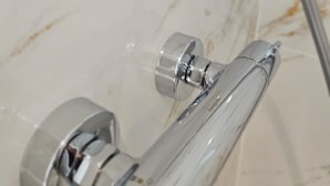 Ett badrum med en duschavdelning med glasväggar, kromade detaljer och väggar klädda i marmor.