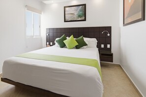 Een hotelkamer met een groot bed, een hoofdbord met een ruitpatroon, een raam en een schilderij aan de muur.
