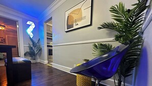 Un salon moderne avec un lampadaire bleu, un parquet en bois et une œuvre d’art abstraite accrochée au mur.