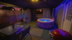 Un espace intérieur accueillant avec un jacuzzi, une table à manger et des chaises.
