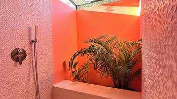A bathroom with a shower, a sink, and a plant.