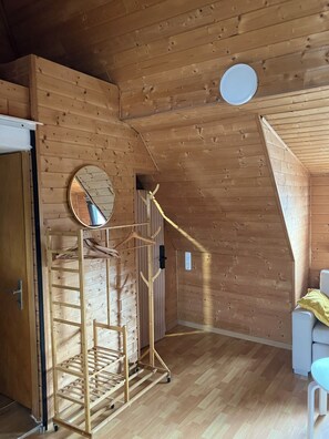 A room with wooden walls and a sloped ceiling, a wooden drying rack, a mirror, and a white chair. - Studio Mondschein - Phantasialand, Therme Euskirchen, the Eifel, Cologne, and Bonn (Weilerswist)