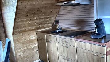 Een kleine keuken met houten kastjes, een spoelbak en een raam.