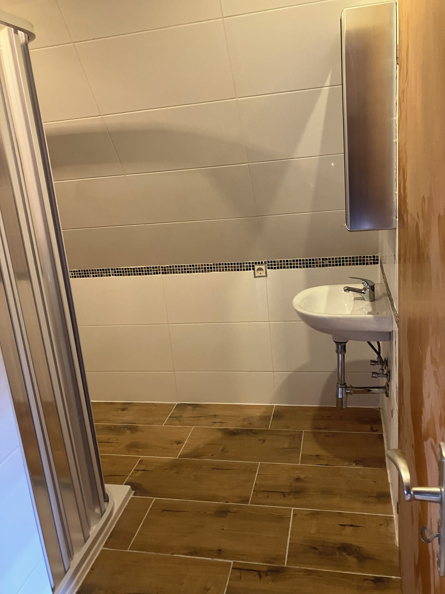 Ein Badezimmer mit Dusche, Waschbecken und Spiegel.