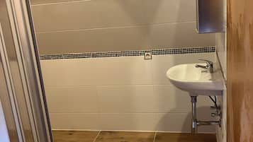 Ein Badezimmer mit Dusche, Waschbecken und Spiegel.