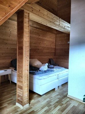 A wooden interior with a bed, pillows, a bedside table, and a small desk. - Studio Mondschein (Weilerswist)