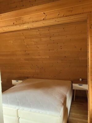 Ein Zimmer mit einem Bett, einem kleinen Schreibtisch und einer Holzbalkendecke.