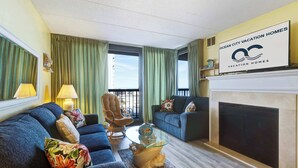 Ein Wohnzimmer mit Kamin, zwei Sofas, einem Glastisch und einem Sessel.