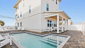A two-story white building with a swimming pool and outdoor seating area. - Chat N Chill Beach Retreat Pool, Beachfront, Private Beach (Panama City Beach)