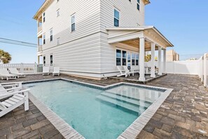 Un edificio blanco de dos pisos con piscina y zona de estar al aire libre.