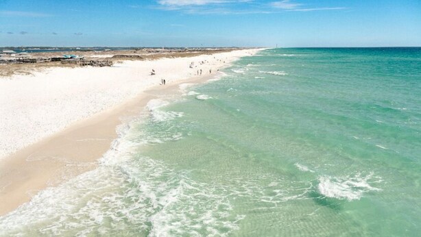 A beach with clear turquoise water, sandy shore, and a pier in the background. - New 2026 listing! Pool, private balcony with big water views, steps to the beach (Navarre Beach)