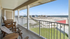 A covered balcony with wooden chairs, a door, and a view of the beach and ocean. - New 2026 listing! Pool, private balcony with big water views, steps to the beach (Navarre Beach)