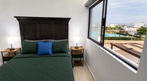 A bedroom with a large bed, two bedside tables, and a view of a swimming pool. - Casa Guacamaya Azul | Corner Home with Clubhouse and Pool Access (La Paz)
