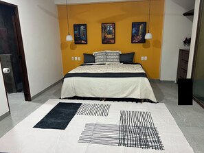 A bedroom with a bed, a rug, and three paintings on the wall. - Brand new studio condo welcomes you to San Pancho, Nayarit, Mexico! (San Francisco)