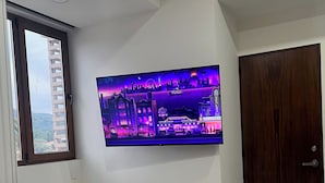 Ein Flachbildfernseher an einer Wand in einem Raum mit einer Holztür und einem Fenster mit Holzrahmen.
