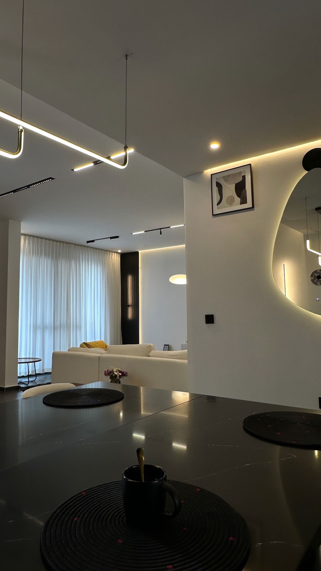 A modern living room with a sofa, a coffee table, and a dining area with a black mug.