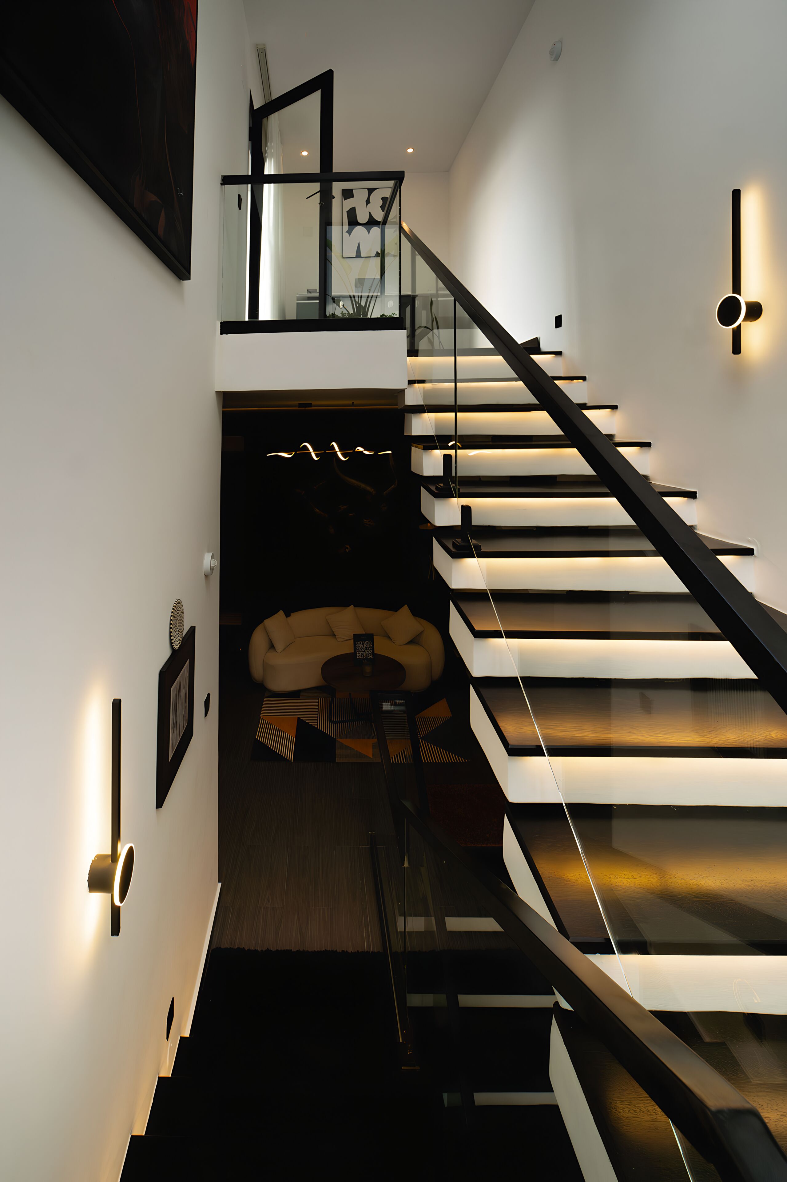 A modern staircase with glass railings, a sofa, and a coffee table in the background.