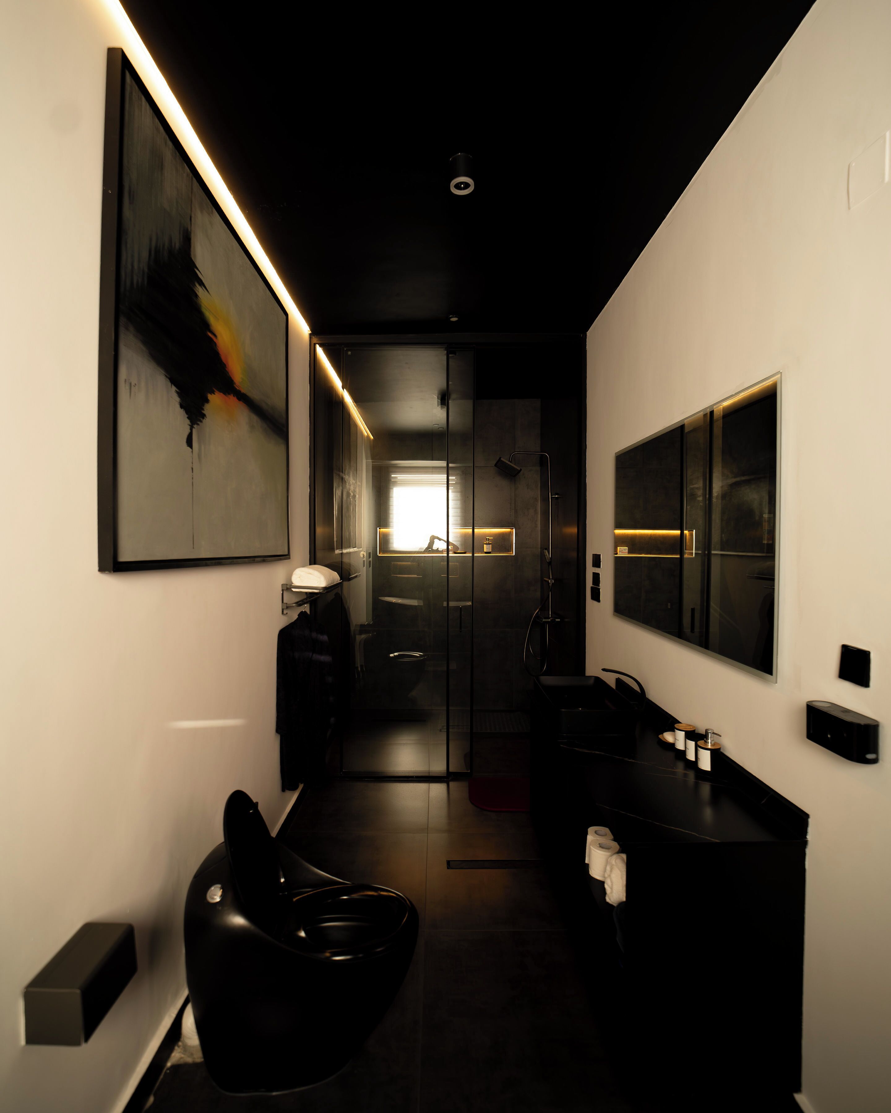 A modern bathroom with a large mirror, a black chair, and a minimalist design.