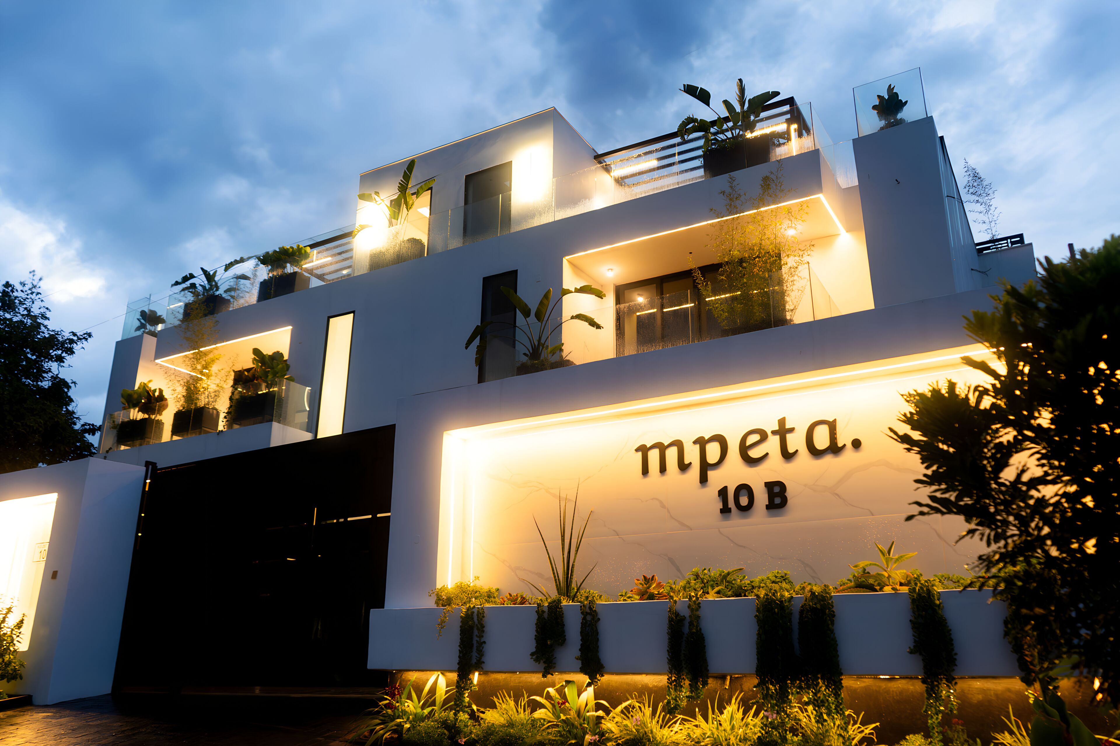A modern building with a sign reading 'mpeta 10B' and multiple balconies with plants.