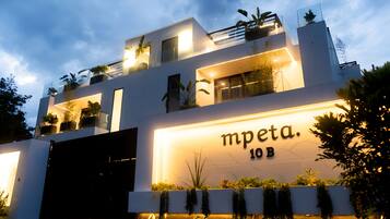 A modern building with a sign reading 'mpeta 10B' and multiple balconies with plants.