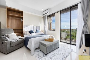 A modern bedroom with a bed, a sofa, a small ottoman, a wardrobe, and a balcony with a view. - Close to Mactan Airport. Peaceful community and stunning views. (Lapu-Lapu)
