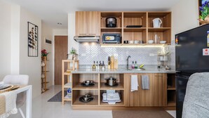 Une cuisine moderne avec des meubles en bois, un four encastré et un réfrigérateur noir.