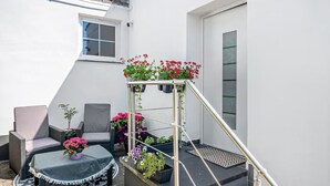 A small outdoor seating area with a table and chairs, a flower planter, and a metal staircase.