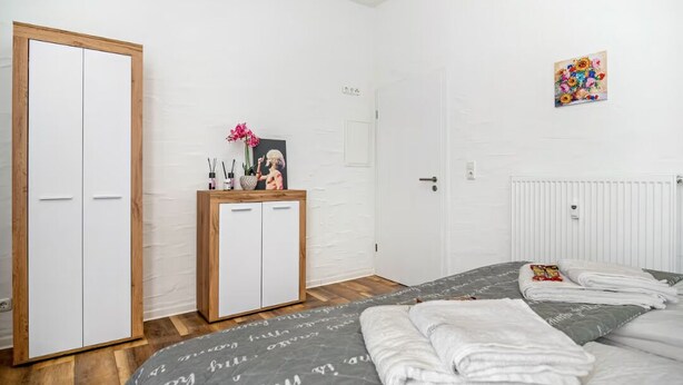 A bedroom with a bed, a wardrobe, a bedside table, and a radiator.