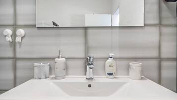 Ein Badezimmer mit einem weißen Waschbecken, einem Spiegel und zwei Seifenspendern.