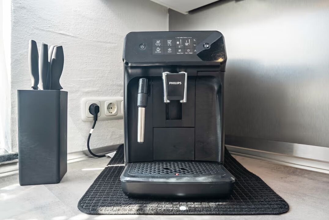 A coffee machine with a water reservoir and a coffee pot on a mat.