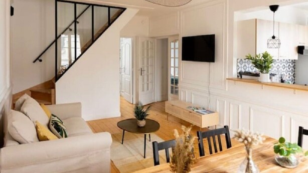 Een moderne woonkamer met een bank, een eettafel en een trap.