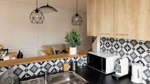 Een moderne keuken met een zwart-wit betegelde achterwand, houten kastjes en twee hanglampen.