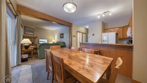 A spacious kitchen with wooden cabinets, a dining table, and a bar area. - Cozy Kimberley Condo with Private Hot Tub (Kimberley)