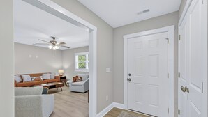 A spacious living room with a sofa, a coffee table, and a ceiling fan. - King bed, EV charger, minutes from UNCW, ILM Airport, area beaches and downtown. (Wilmington)