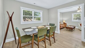 A dining area with a table set for four, surrounded by chairs with green upholstery. - King bed, EV charger, minutes from UNCW, ILM Airport, area beaches and downtown. (Wilmington)