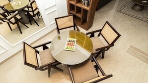 Uma mesa redonda de vidro com um tabuleiro de temperos, rodeada por quatro cadeiras de vime com assentos almofadados.