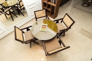 Una mesa redonda de vidrio con una bandeja de condimentos, rodeada por cuatro sillas de mimbre con asientos acolchados.