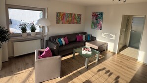 A modern living room with a sofa, armchair, coffee table, and potted plants. - Modern, well-equipped 5* vacation apartment on the sunny side of Linz am Rhein (Linz am Rhein)