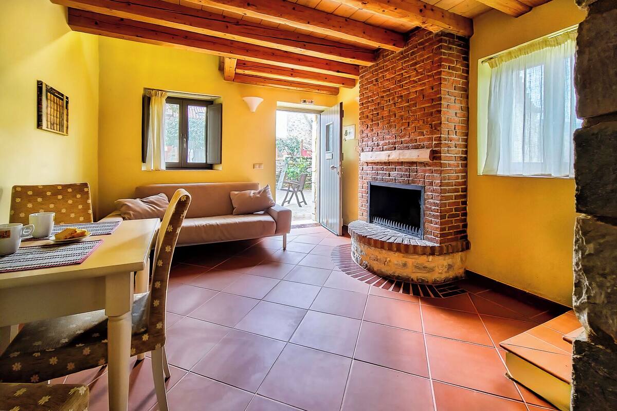 Une pièce chaleureuse avec une cheminée en briques, des murs jaunes et un plafond en bois.