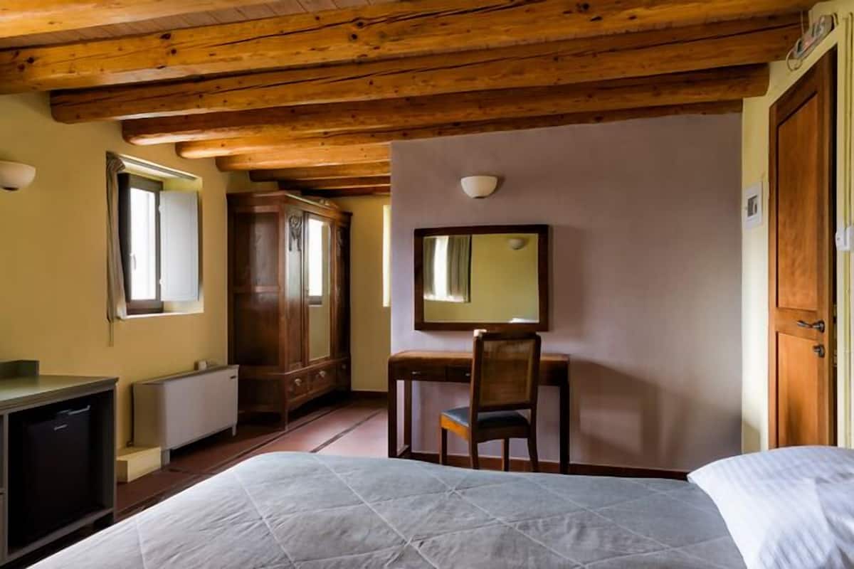 Une chambre à coucher comprenant un lit, un bureau, une chaise, une armoire et un miroir.
