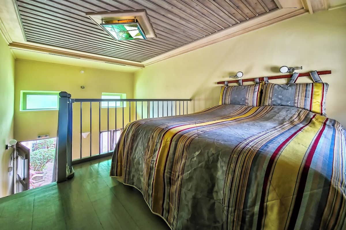Une chambre avec un grand lit, un balcon et une fenêtre de toit.